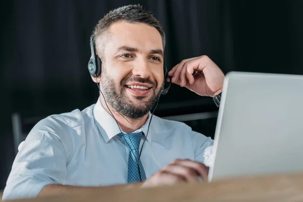 Smiling support hotline worker with laptop and microphone at work — Stock Photo