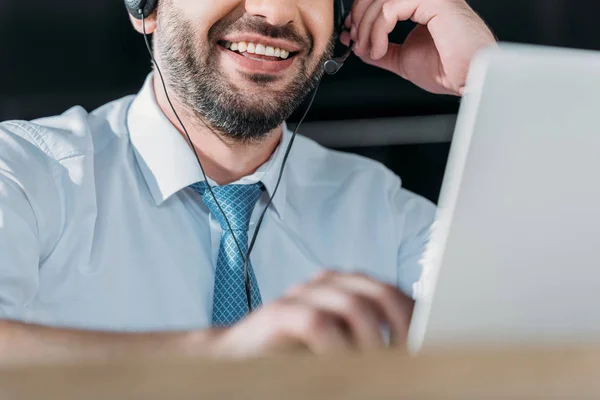 Schnappschuss eines lächelnden Support-Hotline-Mitarbeiters mit Laptop und Mikrofon bei der Arbeit — Stockfoto