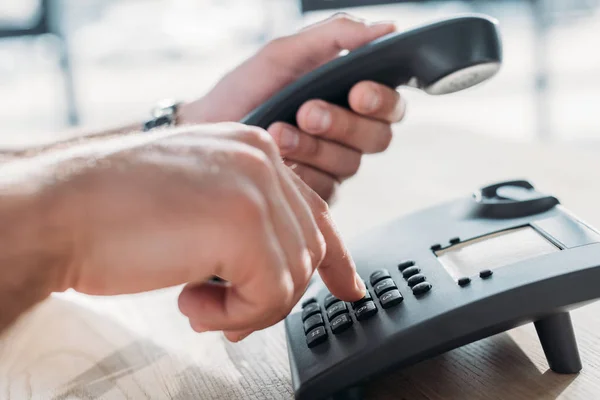 Abgeschnittene Aufnahme eines Mannes, der zum Telefonieren ein stationäres Telefon wählt — Stockfoto