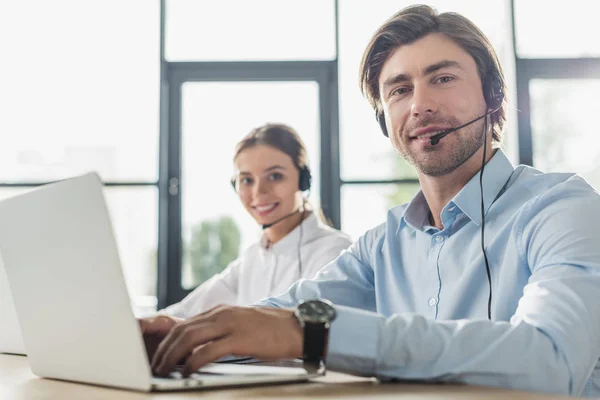 Male and female call center managers working together at modern office and looking at camera — Stock Photo