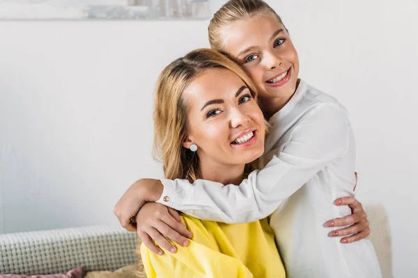 Mutter und Tochter umarmen sich und blicken zu Hause in die Kamera — Stockfoto