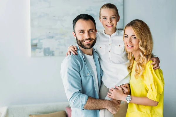 Glückliche junge Familie, die zu Hause zusammensteht und in die Kamera schaut — Stockfoto