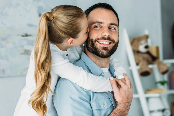 Adorable little daughter embracing father from behind and kissing him — Stock Photo