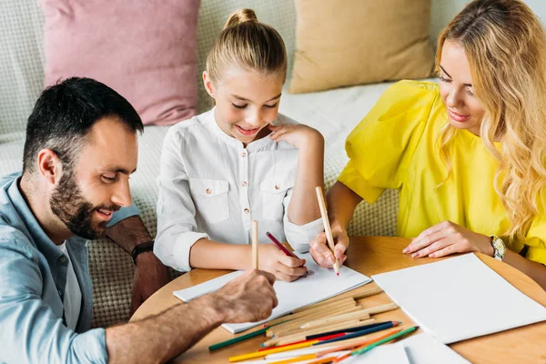 Feliz joven familia dibujo con lápices de color juntos en casa - foto de stock