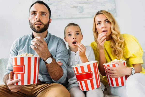 Geschockte junge Familie schaut Film zu Hause mit Eimern Popcorn — Stockfoto