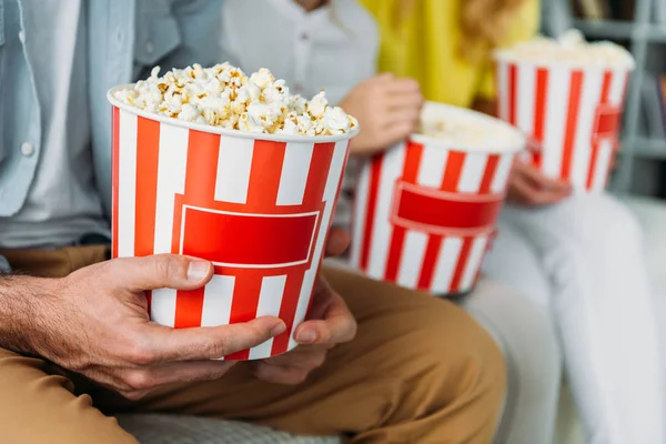 Cropped shot of family sitting with buckets of popcorn — Stock Photo