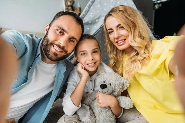 Punto di vista di felice giovane famiglia prendendo selfie a casa con teepee su sfondo — Foto stock