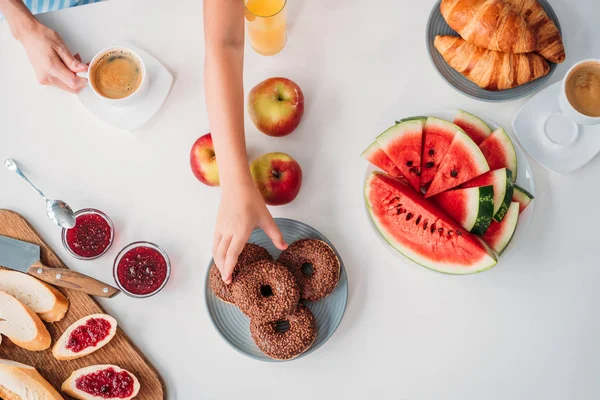 Cropped shot of child reaching for donut during dinner with mother — Stock Photo