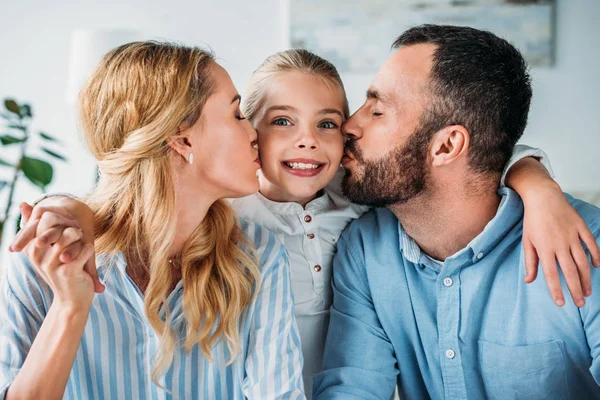 Happy young parents kissing their daughter in from sides — Stock Photo