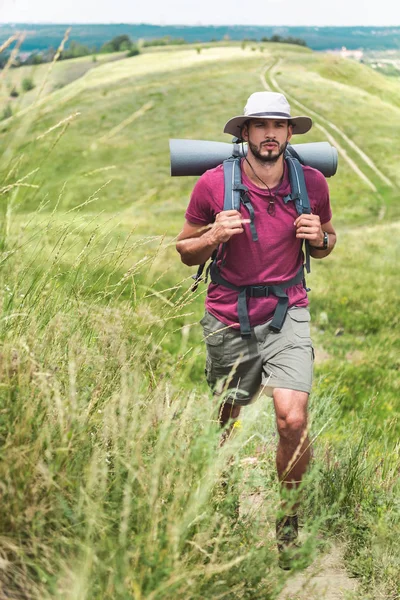 Traveler in hat with backpack and tourist mat at summertime — Stock Photo