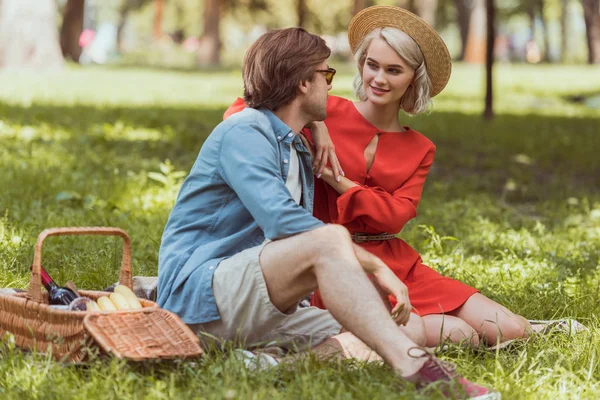 Пара сидит и обнимается на одеяле в парке — стоковое фото
