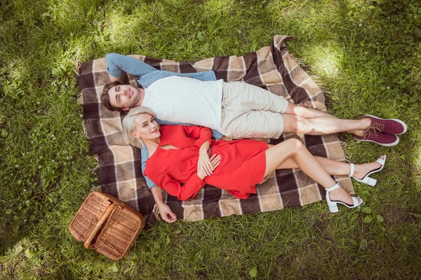 High angle view of girlfriend and boyfriend lying on blanket in park — Stock Photo