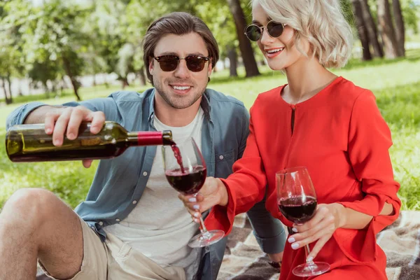 Novio verter vino tinto en copas en el parque - foto de stock