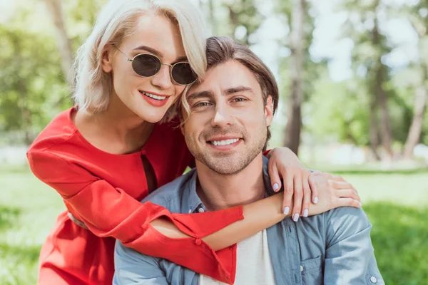 Portrait of smiling couple hugging in park and looking at camera — Stock Photo