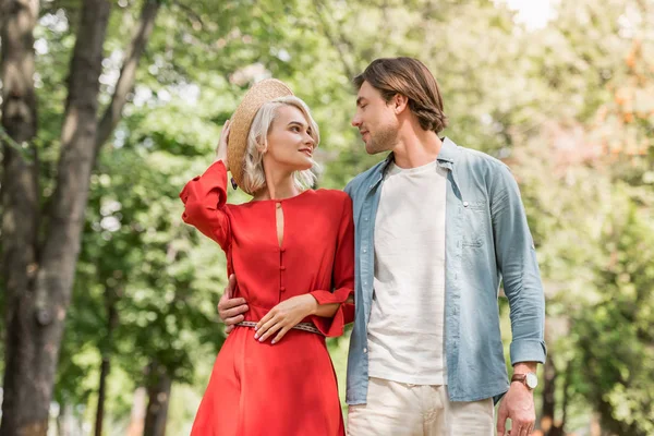 Affectionate girlfriend and boyfriend walking together in park and looking at each other — Stock Photo