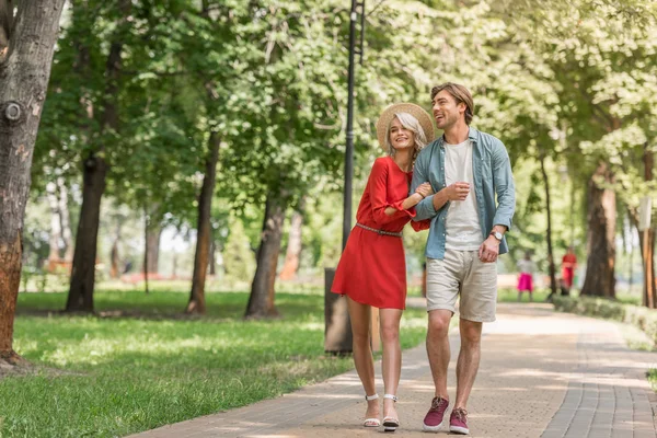 Счастливая девушка и парень, гуляющие вместе в парке — стоковое фото