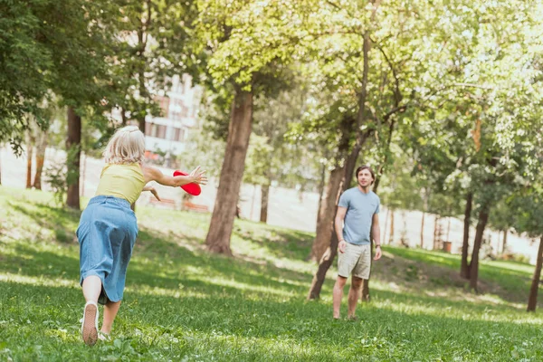 Young couple playing frisbee in park in summer — Stock Photo