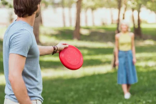 Young couple playing frisbee with red frisbee disk in park — Stock Photo