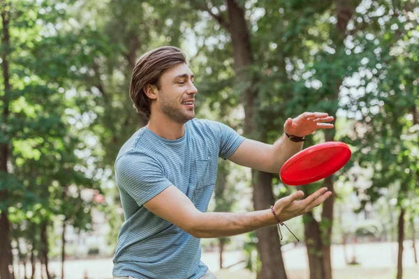 Handsome man catching frisbee disk in park — Stock Photo