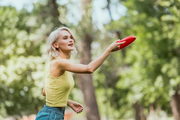 Приваблива дівчина кидає фрібі диск в парку — стокове фото