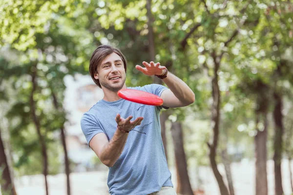 Bonito homem captura disco frisbee no parque — Fotografia de Stock