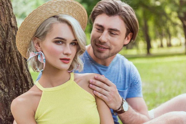 Novio abrazando novia en paja sombrero en parque - foto de stock