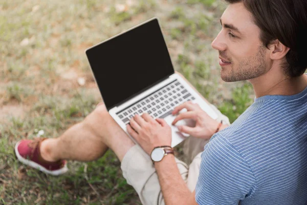 Schöner Mann sitzt im Park und benutzt Laptop — Stockfoto