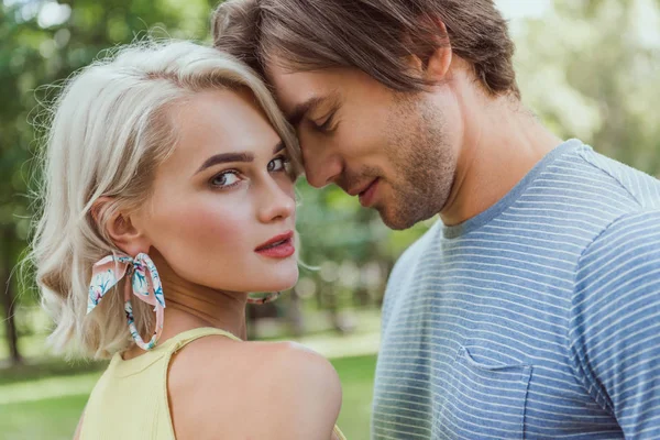 Cariñosa pareja tocando con cabezas en parque - foto de stock