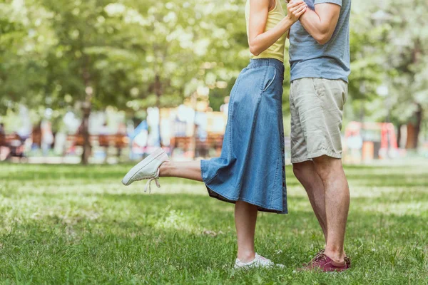 Cropped image of couple standing on grass in park — Stock Photo