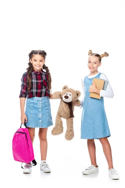 Schoolchildren holding teddy bear and looking at camera isolated on white — Stock Photo