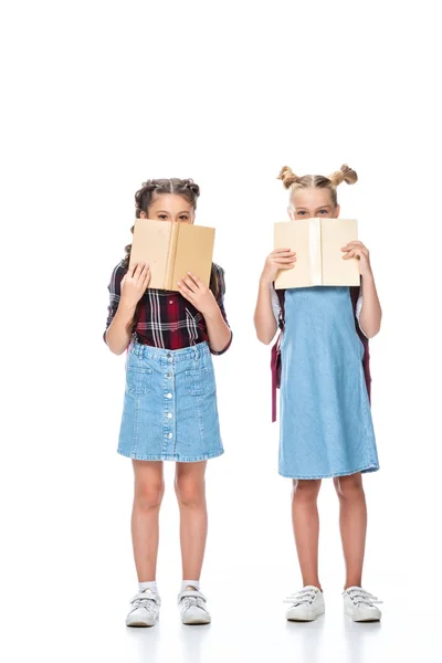 Escolares mirando hacia fuera de los libros aislados en blanco - foto de stock