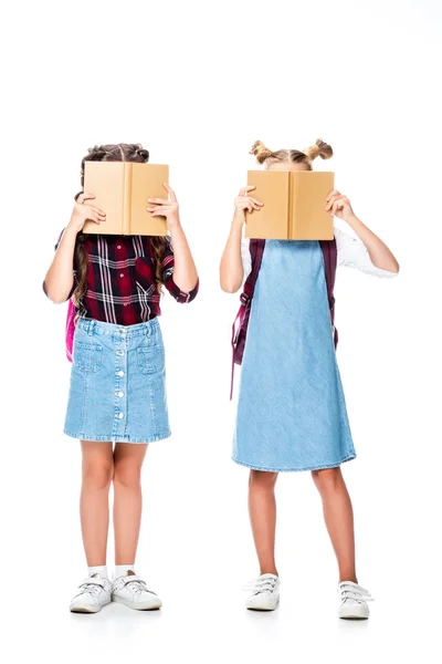 Escolares cubriendo rostros con libros aislados en blanco - foto de stock