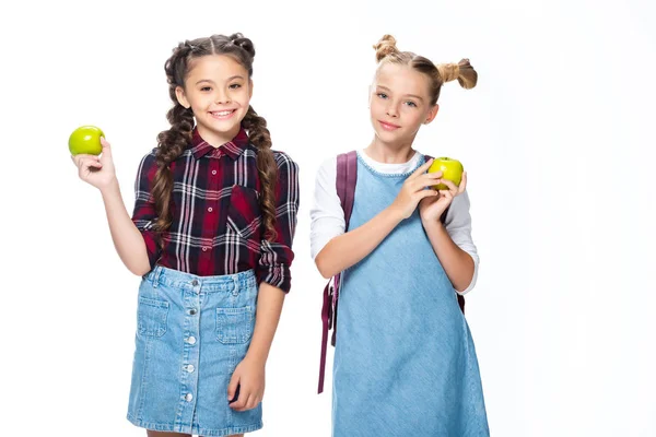 Crianças em idade escolar sorrindo segurando maçãs e olhando para a câmera isolada no branco — Fotografia de Stock