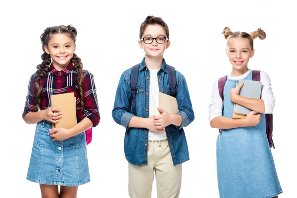 Drei lächelnde Klassenkameraden, die Bücher in der Hand halten und vereinzelt in die Kamera schauen — Stockfoto