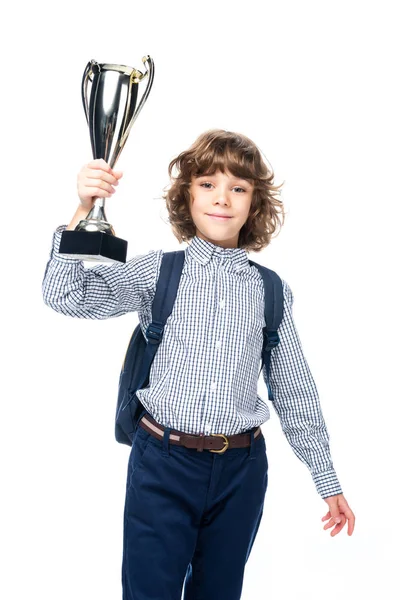 Cheerful schoolboy with backpack holding winner cup isolated on white and looking at camera — Stock Photo