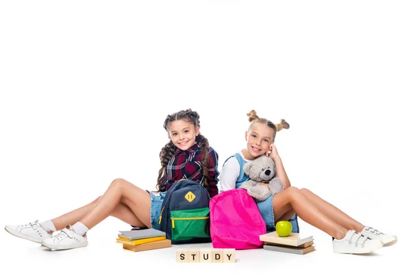 Écoliers assis avec des sacs à dos et des cubes en bois avec étude de mot isolé sur blanc — Photo de stock