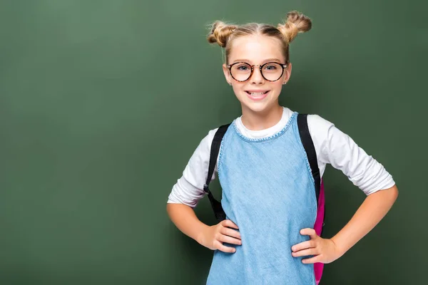 Улыбающийся школьник в очках, позирующий возле доски — стоковое фото