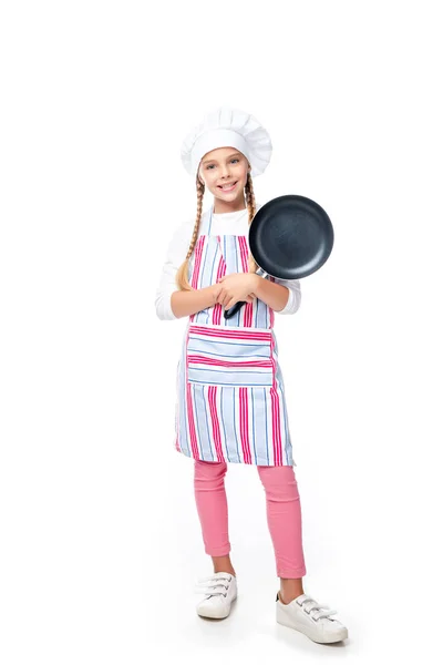 Schulkind im Kostüm des Kochs mit Bratpfanne und Blick in die Kamera isoliert auf weiß — Stockfoto