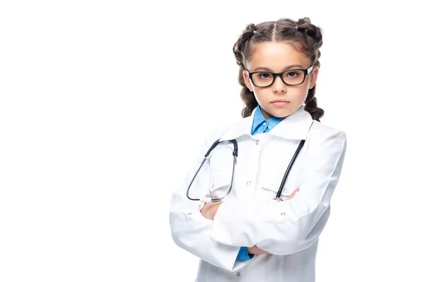 Grave escolar en traje de médico de pie con los brazos cruzados aislados en blanco - foto de stock