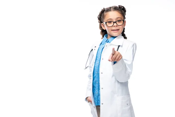Schoolchild in costume of doctor pointing on camera isolated on white — Stock Photo