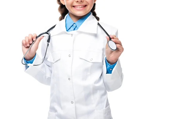 Abgeschnittenes Bild eines Schulkindes in weißem Mantel, das Stethoskop isoliert auf weiß hält — Stockfoto