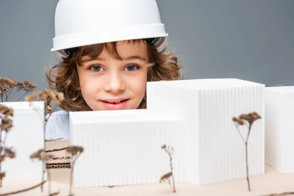 Schoolboy in costume of architect near model of buildings isolated on white — Stock Photo