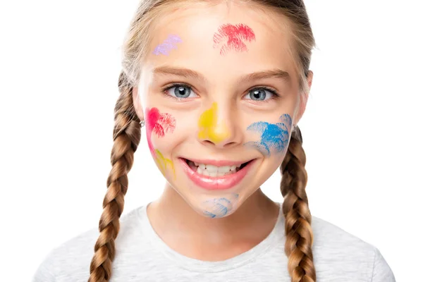 Портрет улыбающегося школьника с красками на лице, смотрящего на камеру, изолированную на белом — стоковое фото