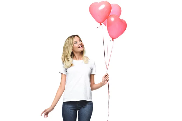 Hermosa chica mirando paquete de globos en forma de corazón aislado en blanco - foto de stock