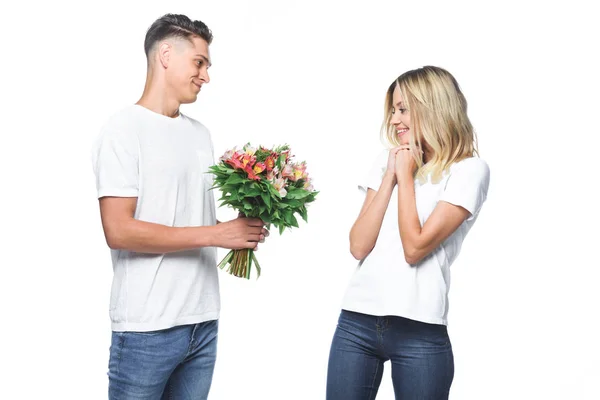 Seitenansicht des Freundes präsentiert Blumenstrauß an überraschte Freundin isoliert auf weiß — Stockfoto