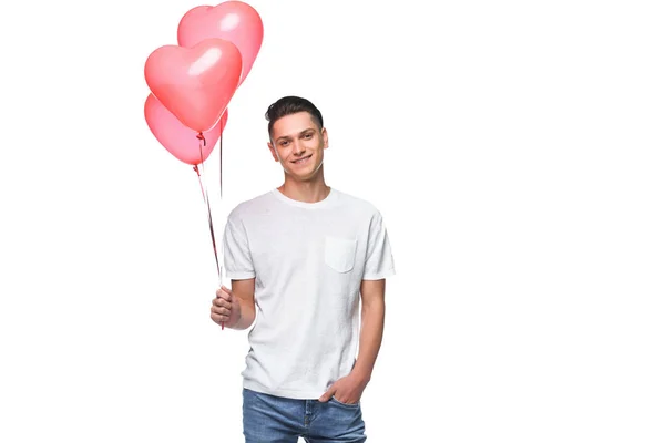 Sonriente hombre de pie con manojo de globos en forma de corazón aislados en blanco - foto de stock