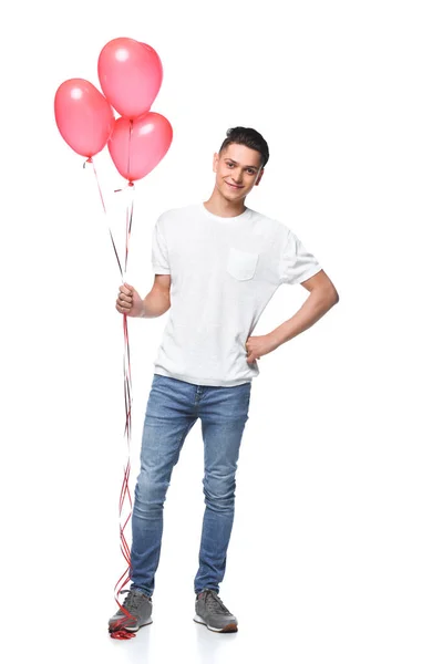 Homem bonito de pé com feixe de balões em forma de coração isolado em branco — Fotografia de Stock