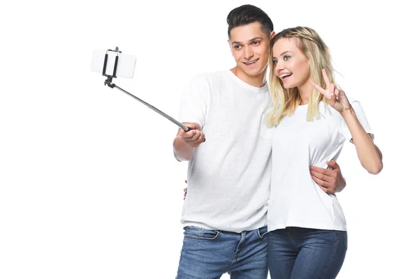 Casal sorrindo tirando foto com smartphone e selfie stick isolado no branco — Fotografia de Stock