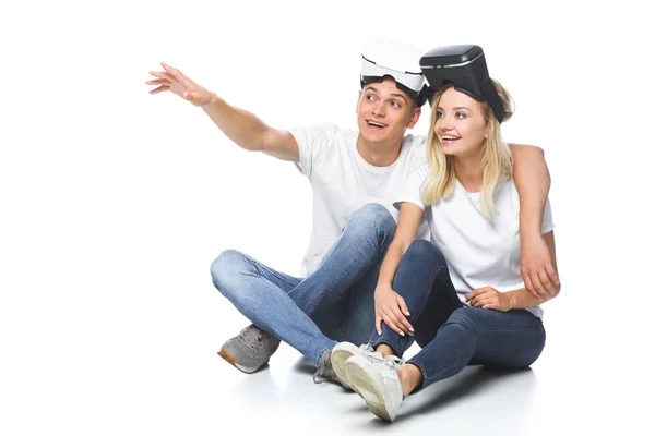 Casal sentado com fones de ouvido realidade virtual e olhando para longe isolado no branco — Fotografia de Stock