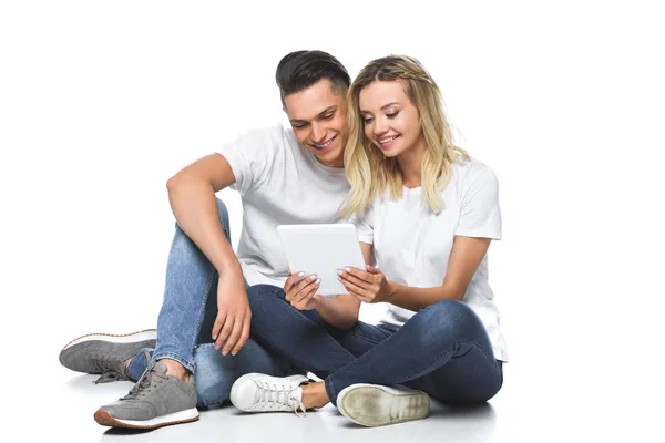 Casal sorridente sentado e usando comprimido em conjunto isolado em branco — Fotografia de Stock